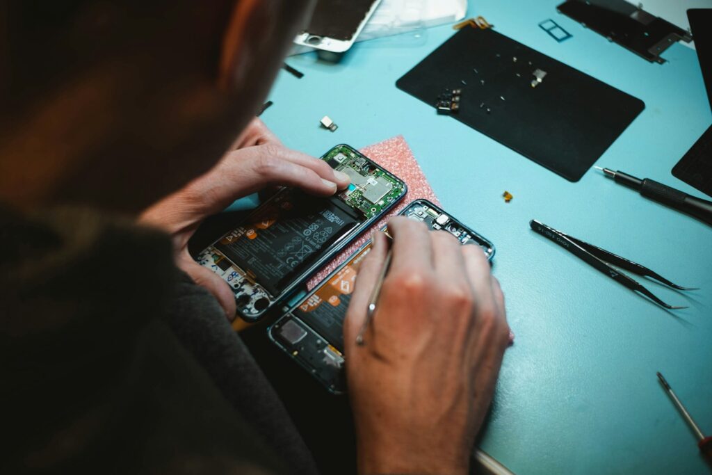 Phone Repair 1 person repairing smartphones under a lighted table