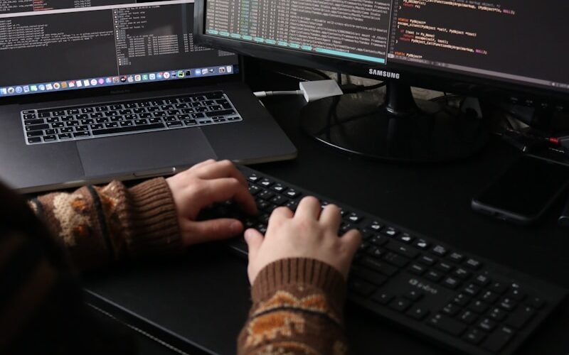 a person sitting at a desk with a laptop and a computer monitor